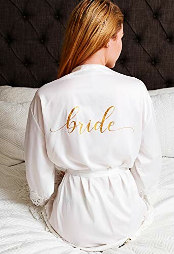 Woman in a white robe with 'bride' written on back sitting on bed.