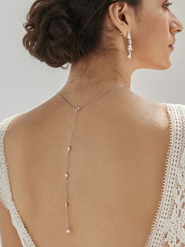 Woman wearing elegant back chain and earrings.