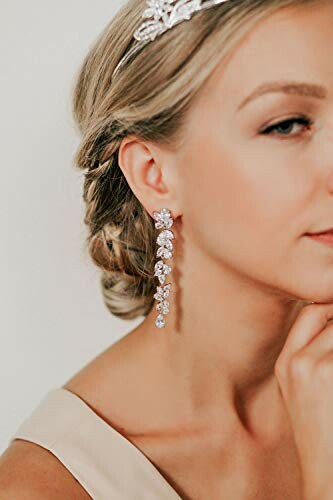 Woman wearing elegant bridal earrings and headpiece.