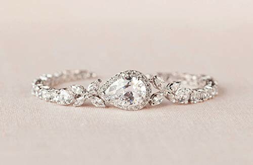 Elegant diamond ring with pear-shaped center stone and intricate band.