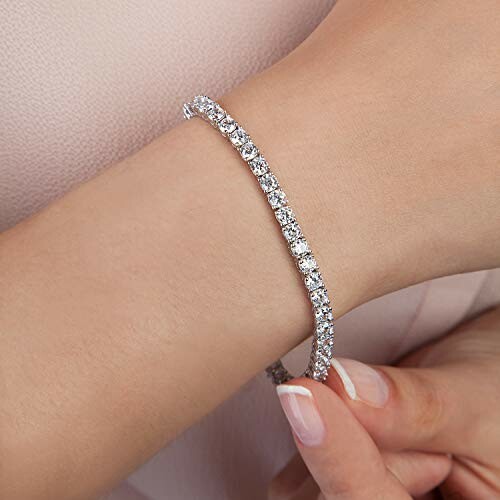 Woman wearing a diamond tennis bracelet on wrist.