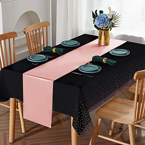 Dining table with black tablecloth, pink runner, plates, napkins, and flower centerpiece.