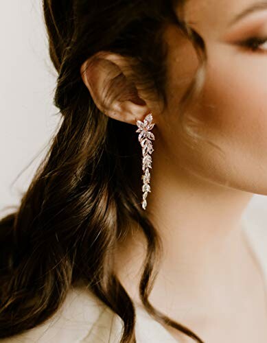 Woman wearing a long, elegant earring with leaf design.