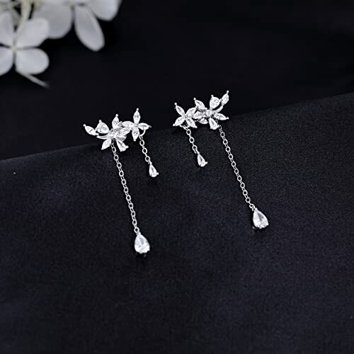 Elegant floral drop earrings with crystals on a dark background.