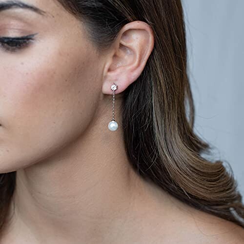 Close-up of a woman wearing a pearl drop earring.