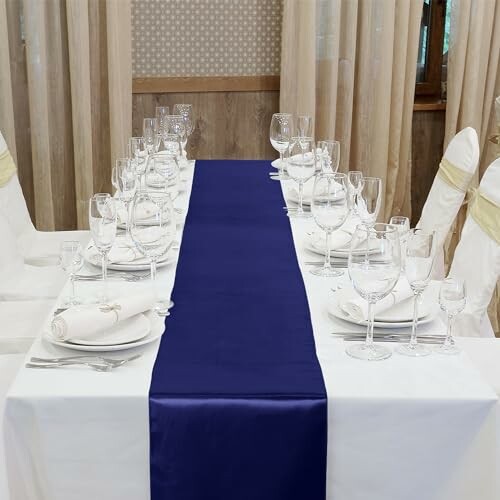 Elegant table setting with white linens, blue runner, and glassware.