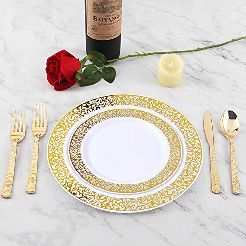 Elegant table setting with gold-trimmed plates, cutlery, a red rose, candle, and wine bottle.