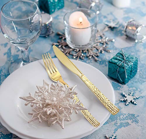 Elegant winter table setting with white plates, gold cutlery, and snowflake decor.