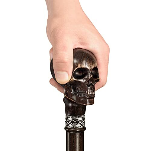 Hand holding a walking cane with a skull-shaped handle.