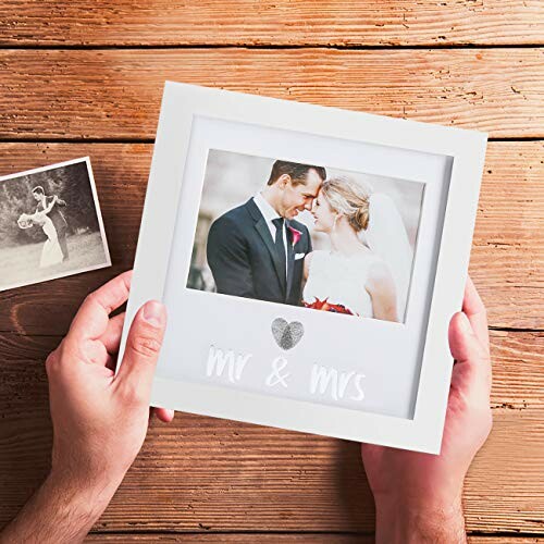 Hands holding a wedding photo frame with a bride and groom.