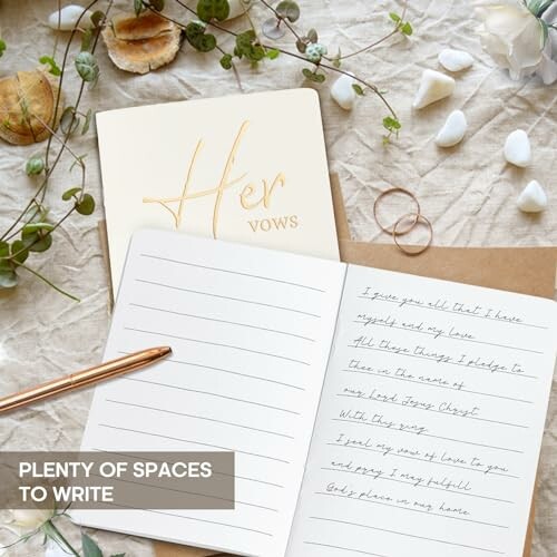 Open notebook with written vows and a 'Her Vows' book surrounded by shells and a plant.