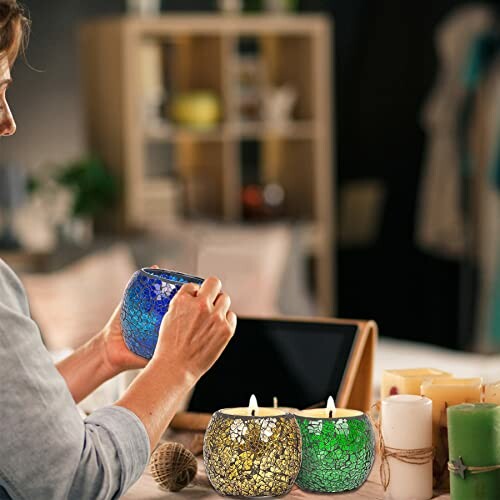 Woman lighting colorful mosaic candles on a table.