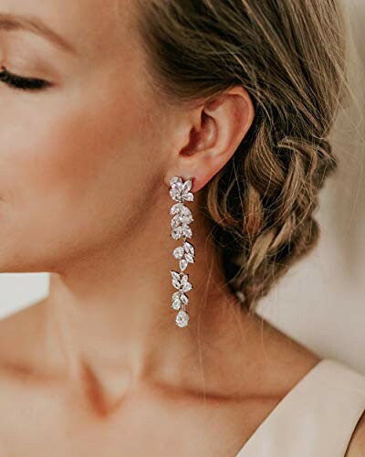 Woman wearing elegant, sparkling drop earrings with a floral design.