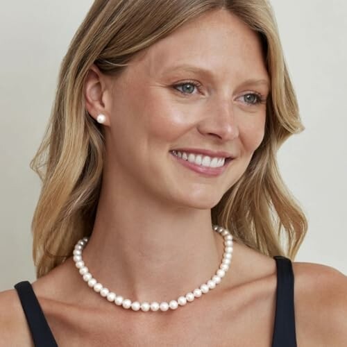 Smiling woman wearing a pearl necklace and earrings.