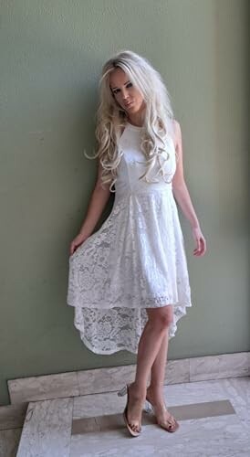 Woman in a white lace dress standing by a wall